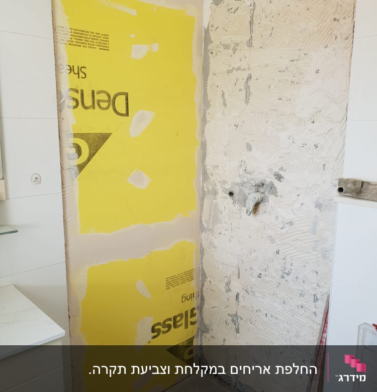 קיר עם לוח גבס צהוב ותשתית טיח חשופה